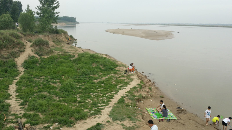 照片上的大堤位于黄河南岸.背景是郑州黄河公路大桥.