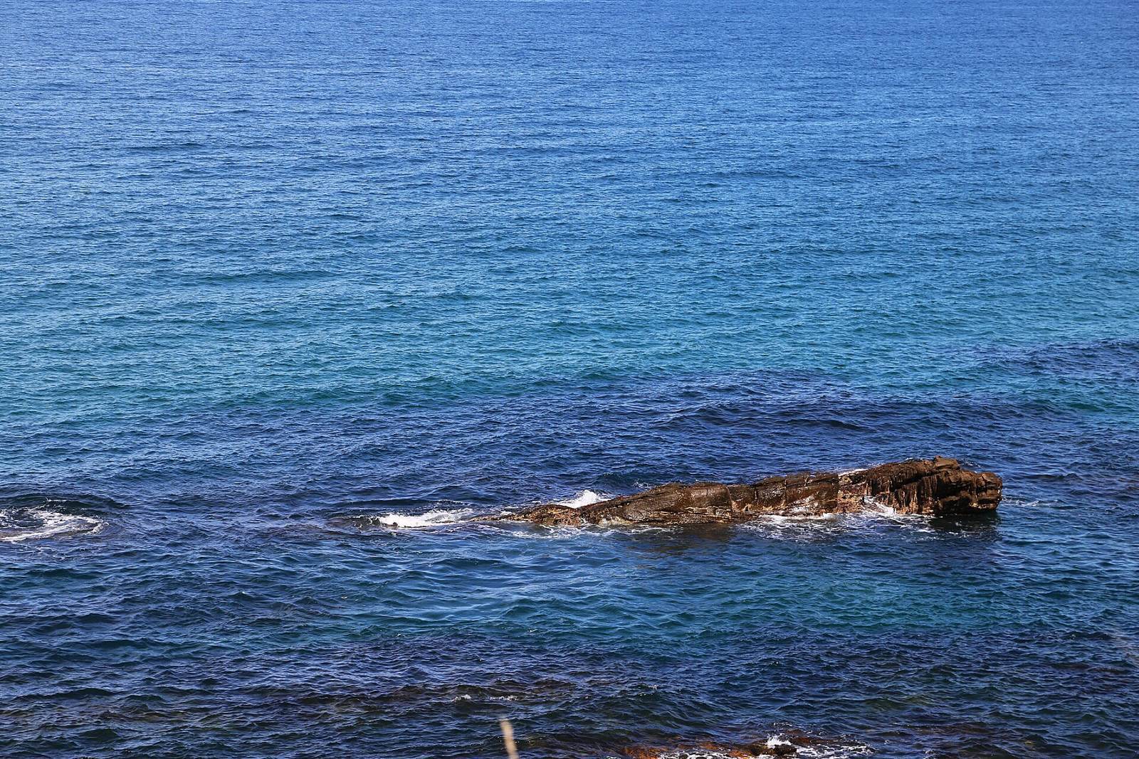 開車在靠山面海的大洋路上兜風,海水蔚藍壯闊,遠近顏色深淺不一,遠處